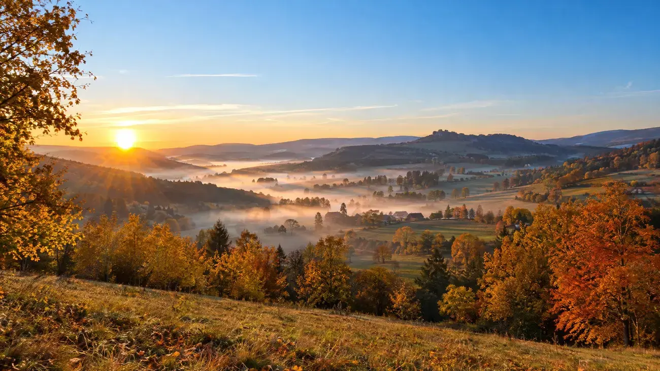 Podzimní krajina za časného rána s nízkou mlhou v údolí během babího léta